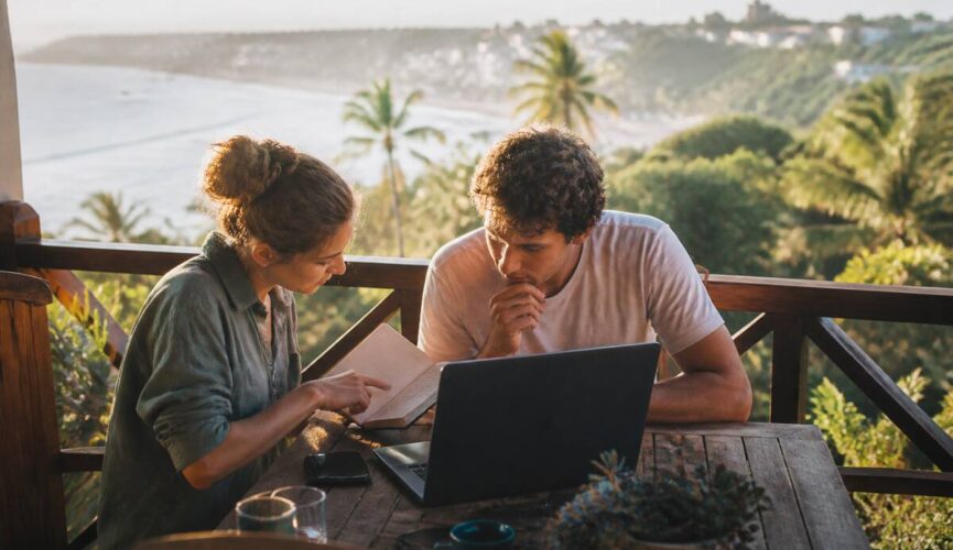 Stel dat vakantie-opties bekijkt op een laptop met uitzicht op zee tijdens een zonsondergang