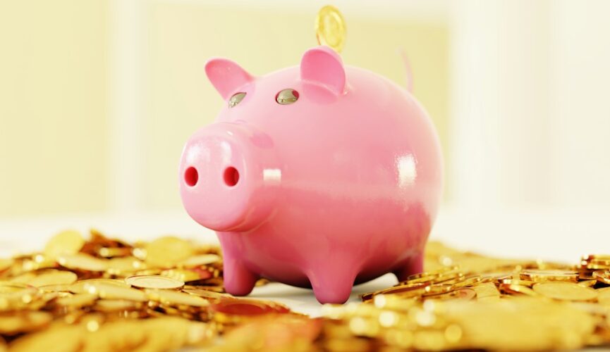 A pink piggy bank surrounded by a pile of gold coins